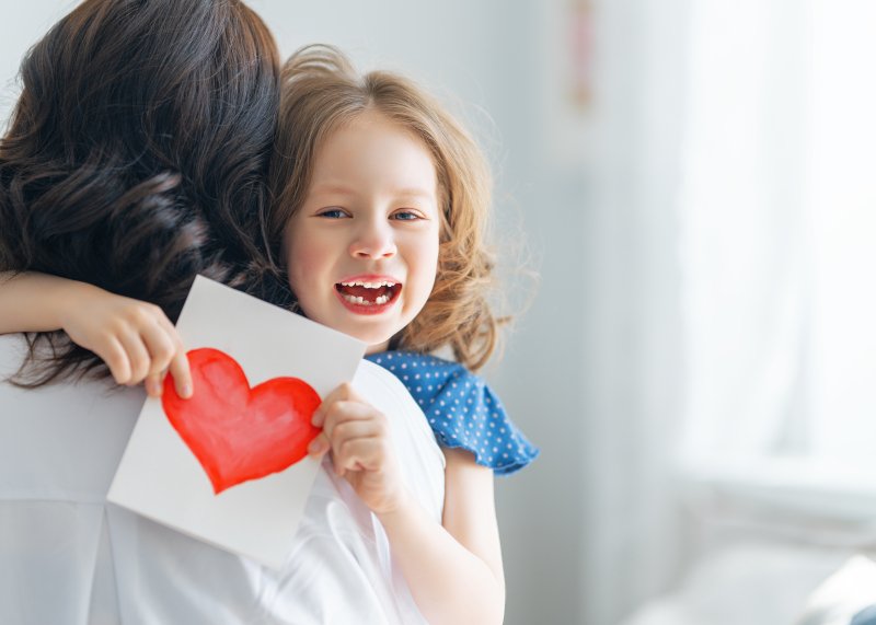 child giving mother mother's day card and hug