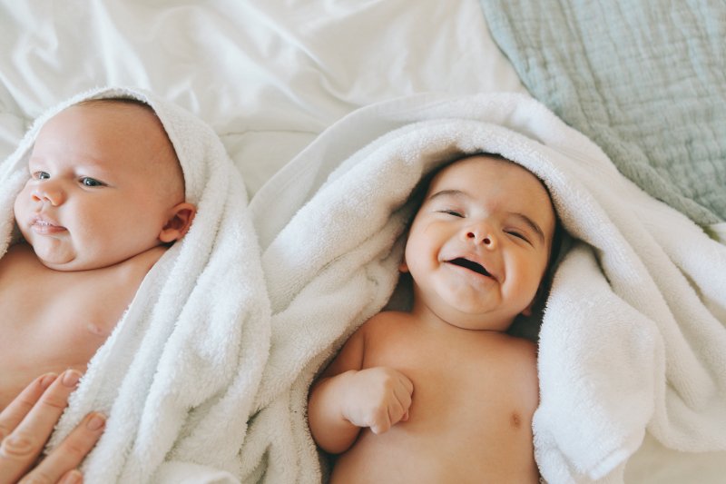 two happy babies swaddled in towels after a bath